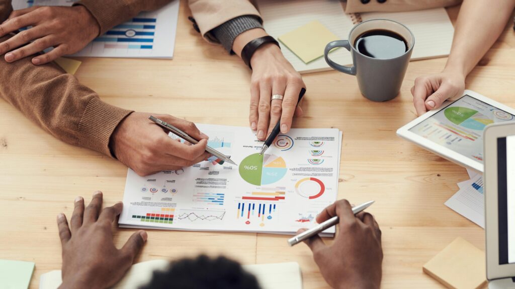 Grupo de pessoas reunidas estudando gráficos que definem um produto de sucesso.